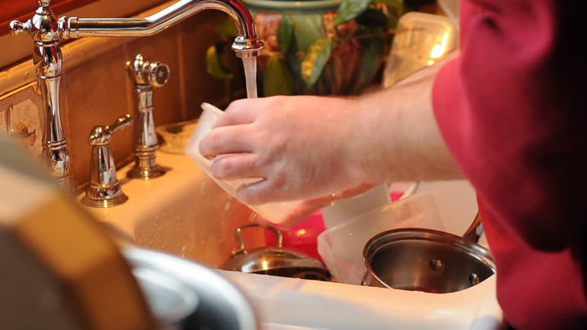 Man Washing Dirty Dishes in the kitchen sink inside of his home. 24fps HD 720p footage shot with Nikon D300s camera.