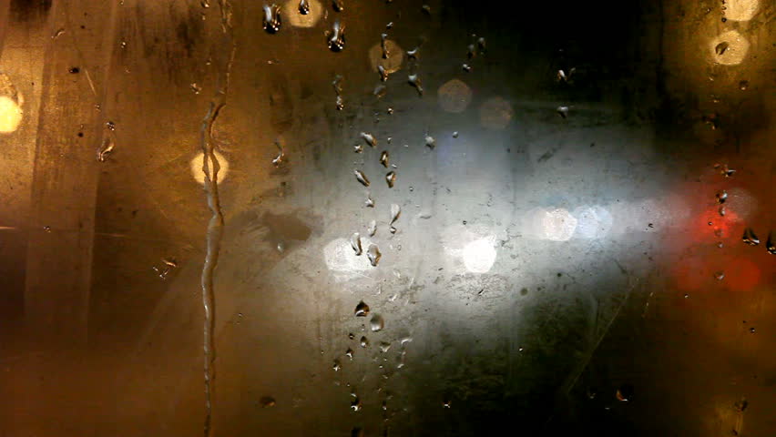 Tram's rear window view. Cold weather cityscape. Night time. Focus on window. Fading out colored blurred lights. Another tram passes by the right side. 