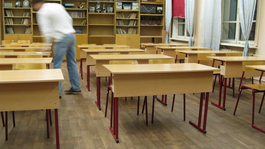 Young teacher places books on school desks and then collects them, time lapse 