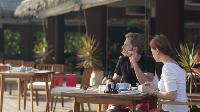 young couple eating breakfast on a tropical island terrace 