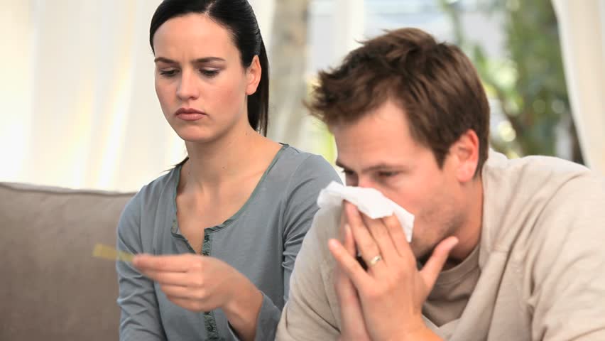 Lovely woman taking the temperature of her husband