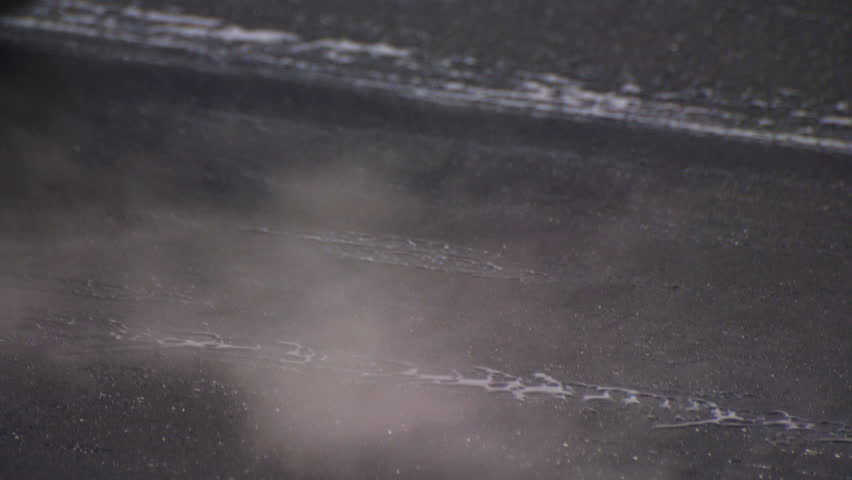 Close-up of steam roller flattening a freshly paved asphalt road at a construction site.