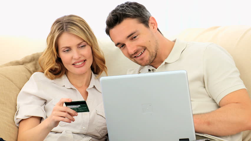 Young couple using a credit card on internet with a laptop
