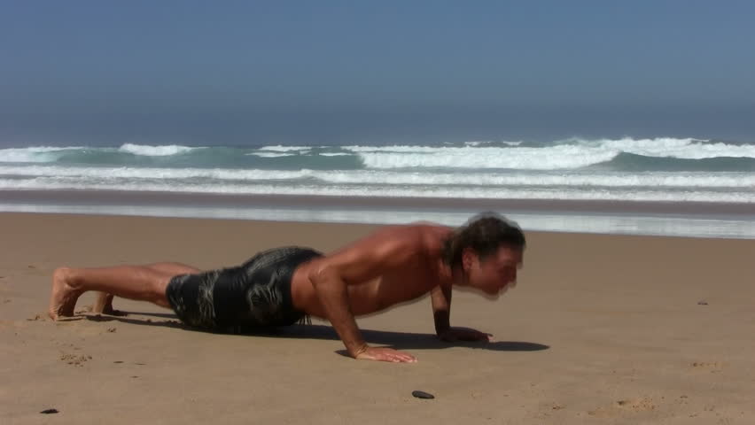 Young fit guy doing push ups on the beach