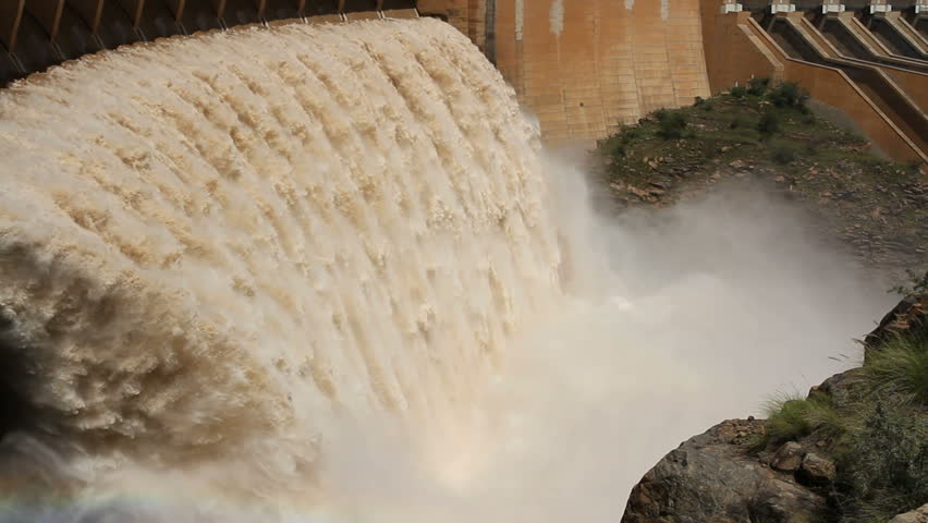 Strong flowing water with water spray and rainbow as water is released from the open sluice gates of a large dam