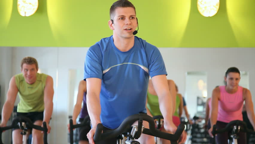 Group of five people - men and women - in gym or fitness club exercising their legs doing cardio training