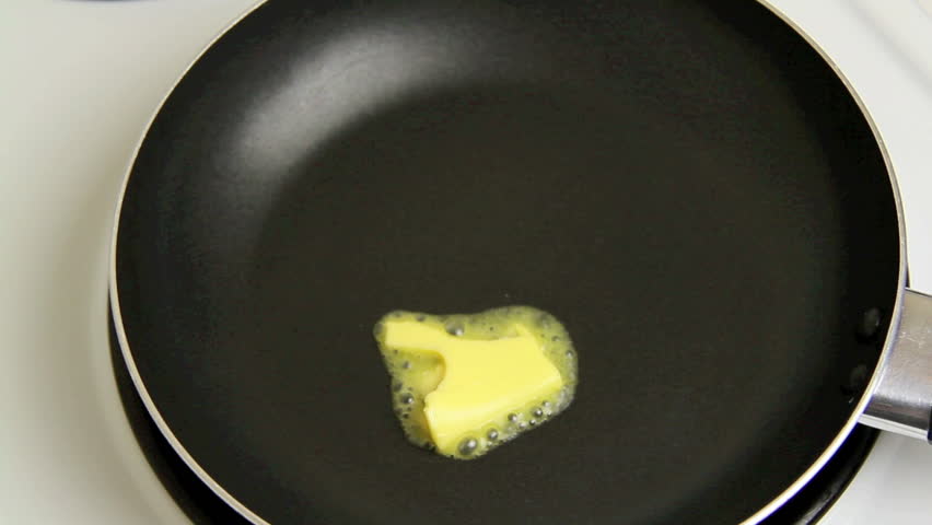 A knob of butter is put into a hot fry pan and melts.