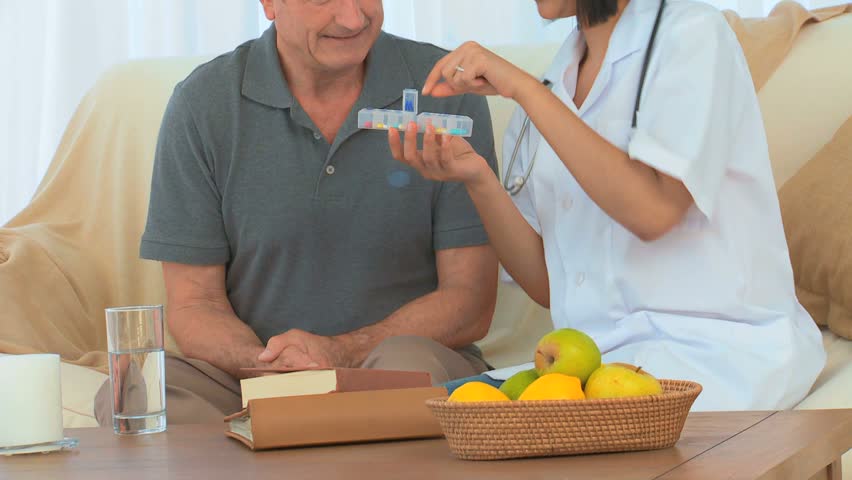 A patient taking his pills next to his nurse