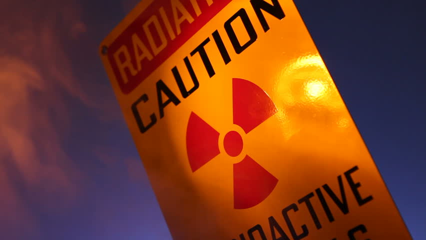 A close up of a radiation warning sign with flashing lights reflected on the sign.