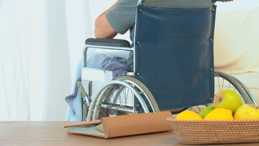 Man in a wheelchair looking through the window at home