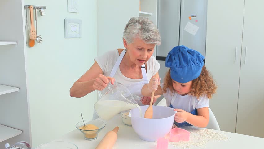 Adorable little child cooking with her grandmother