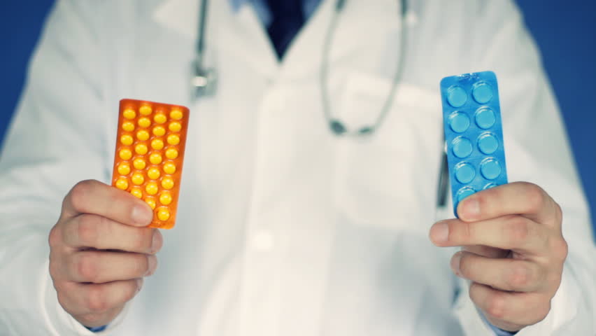 Male doctor hand offering pills in yellow and blue blister