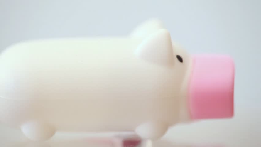 small plastic white piggy with pink snout rolling around its axis