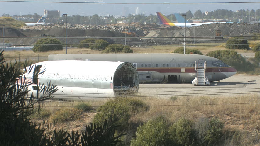 This is a long shot of 2 airplanes sitting in the California sun rusting and rotting. They look like they were dismantled decades ago. The logos have been removed from the new planes in the distance.