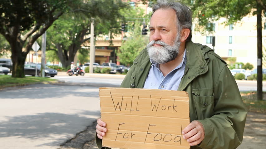 Homeless Vietnam veteran suffering from post traumatic stress disorder uses a homemade sign to beg for food and look for work in an urban area.