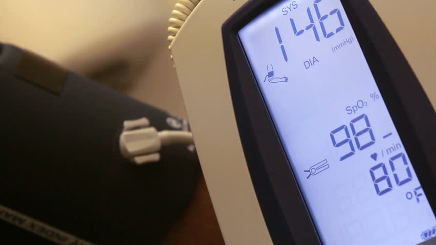 Vital signs displayed on monitor next to patient's arm wrapped with blood pressure cuff. 