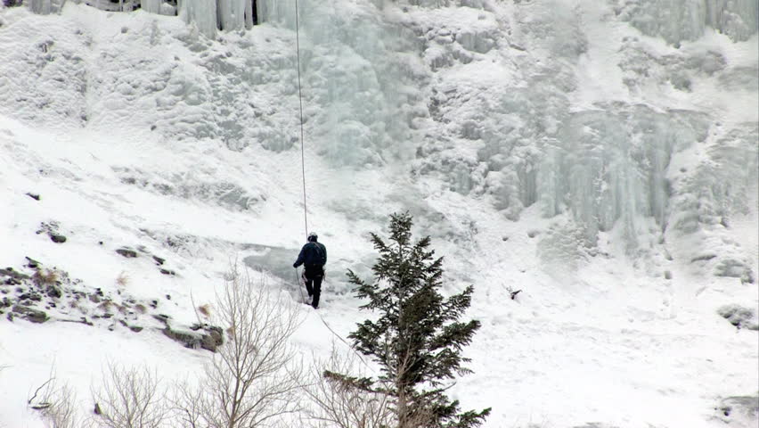 Video of ice climbers climbing ice flow at Bridal Vale Falls in central Utah. Steep rock ledges pan up to climber on frozen waterfall. Athletic sport in cold weather. Wasatch Mountain range. 