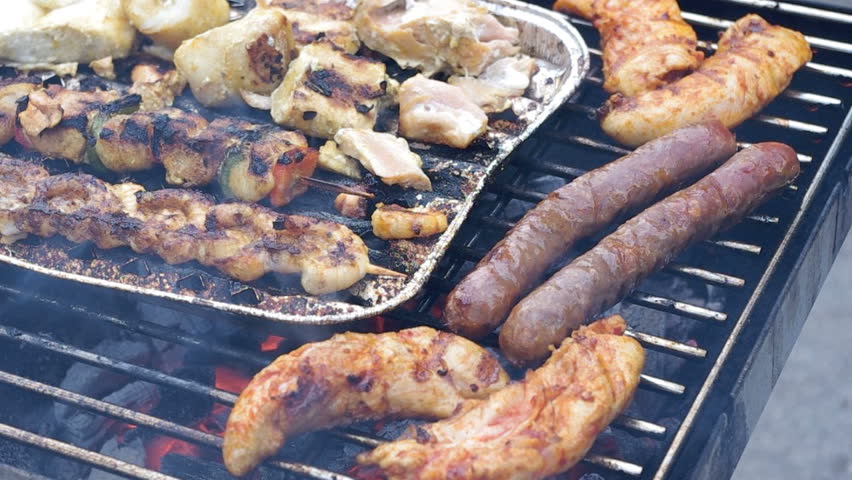 Unhealthy eating: Lightly burned sausage, meat and fish on barbecue grill.