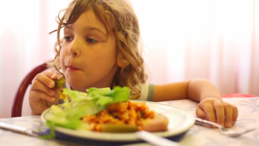 girl in dining room hands eats leaf of lettuce, pizza  and looks around