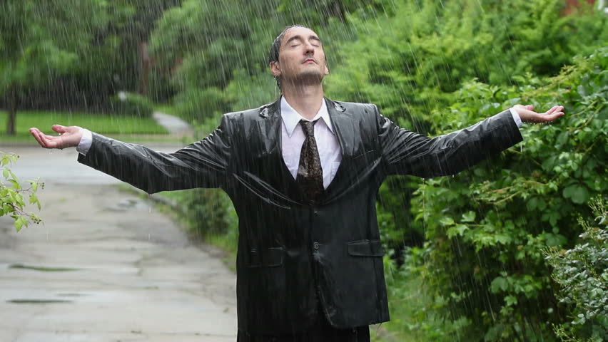 Business man in rain, holding up arms, eyes closed