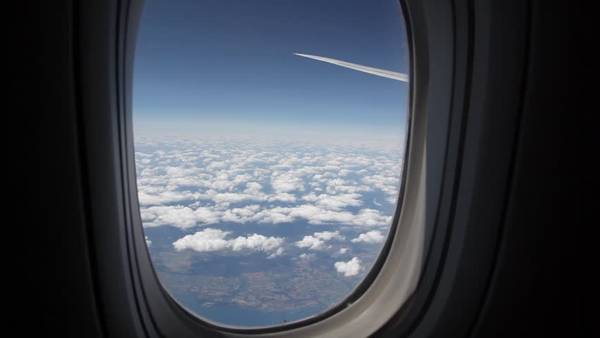 Clouds seen through the window of jet airplane. Airplane flies above the weather