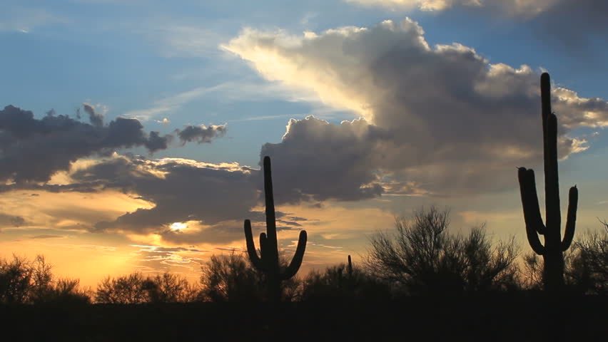 Time Lapse, Clouds swoop across sky as the sun sets over saguaro cactus desert landscape. 