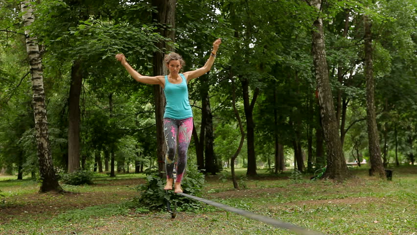 girl balances on the slackline and sits