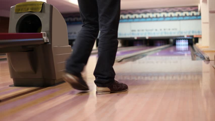 Man throw ball and hit pins in bowling club, parquet floor with reflexions.