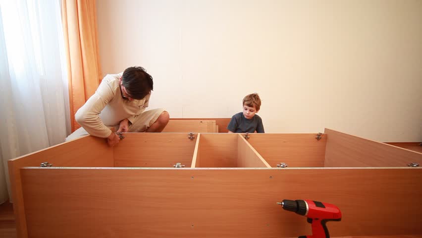 Father and his son construct wooden cabinet at home