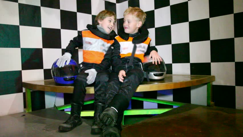 Boys sit in uniform for go-cart racing and wait the beginning of races