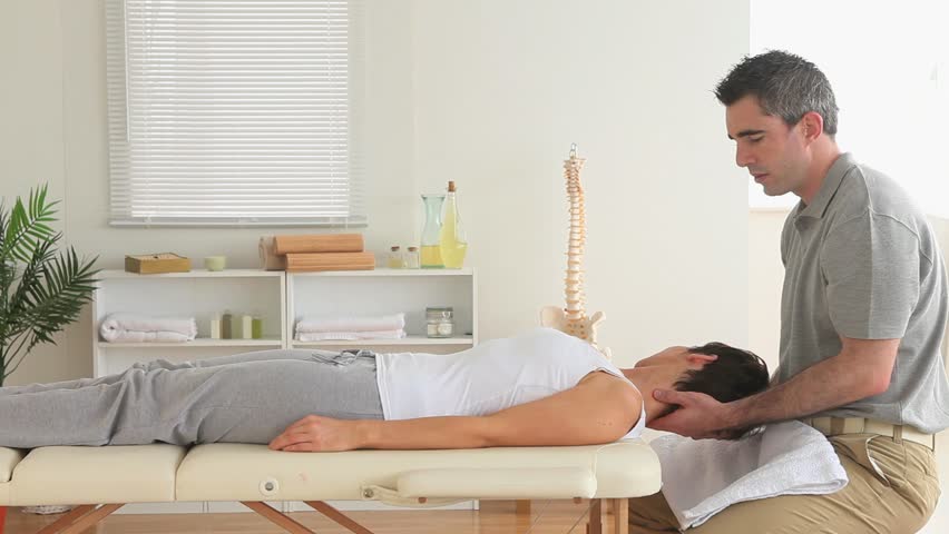 Masseur massaging the neck of a woman in a room