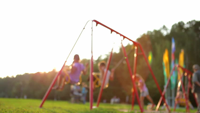 children ride on the swings at the playground. defocused