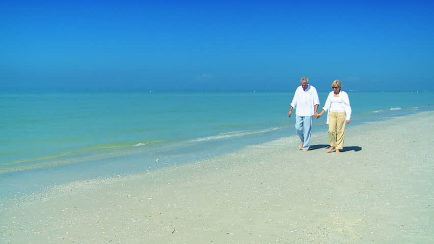 Attractive senior couple confident of the future quietly strolling on the beach filmed at 60FPS