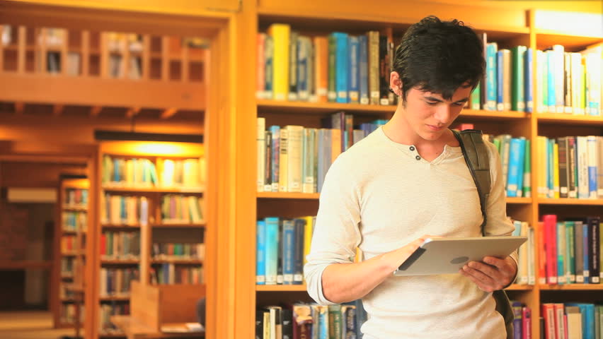 Handsome young man reading a book in a library
