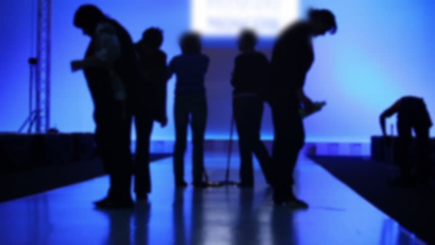 Few people cleaning podium in dark after fashion show  