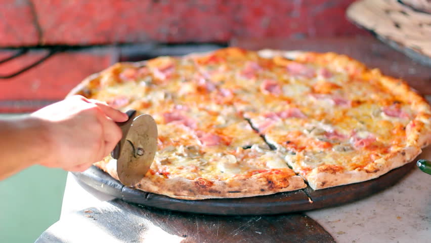 Cutting pizza slices.Pizza ready to be served at the outdoor restaurant. HD 1080i.