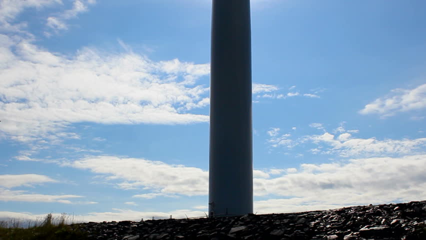 Wind turbine simplicity, pan upward, to silhouetted blades spinning in cloud-streaked sky. 1080p