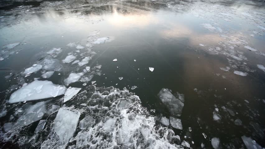 Sail through ice in river, which reflects forest on shore