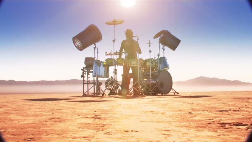 Drummer in desert (front medium shot with sun overhead) 