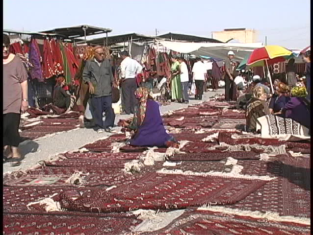 TURKMENISTAN - CIRCA 1990s: People browse the beautiful carpets for sale at the Tolkuchka Bazaar circa 1990s in Turkmenistan.