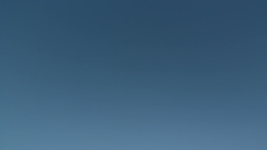 HD footage of a twin engine jet plane passing overhead, with the camera panning to follow it landing into the sunset