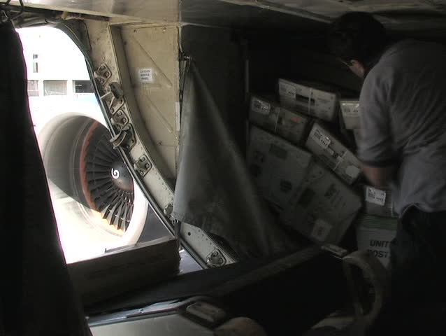 LOS ANGELES, CA - CIRCA 2006: An employee grabs boxes from a conveyor belt and stacks them into the cargo hold of a plane circa 2006 in Los Angeles, CA.