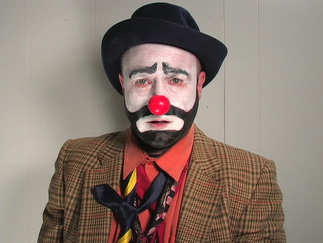 A CLOWN JUGGLING APPLES LOOSES HIS NOSE AS HE TAKES A BITE FROM ONE OF THE APPLES.