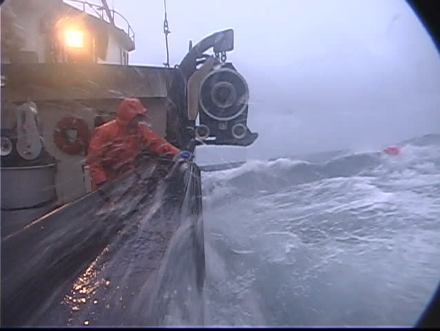 A lobster fishermen throws a rope out and catches a buoy in treacherous conditions while ocean fishing.