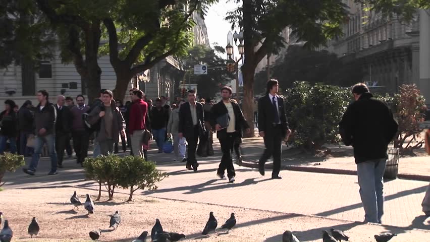BUENOS AIRES, ARGENTINA - CIRCA 2009: Crowds of people walk across a street and through a small park pathway circa 2009 in Buenos Aires, Argentina.