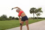 A pretty brunette in fitness wear, with remarkable muscle definition, stretches prior to jogging outdoors.