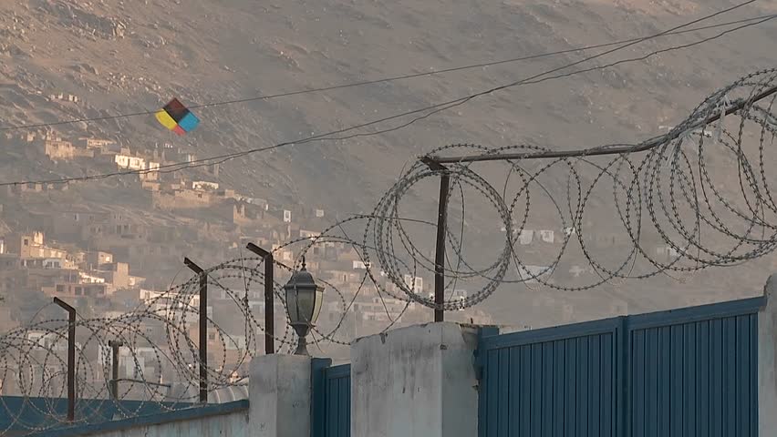 Razor wire and kites flying against a hillside in Kabul, Afghanistan.