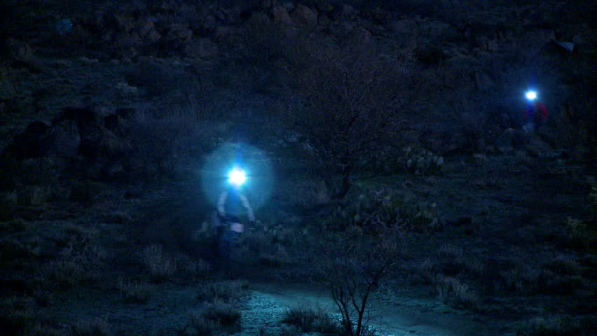 A couple of people ride their bikes at night