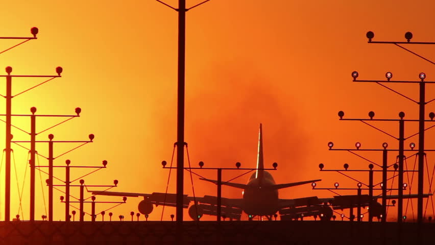 HD footage of a 4 engine jumbo jet plane landing in silhouette against an orange sunset sky.  Jet engine audio included.