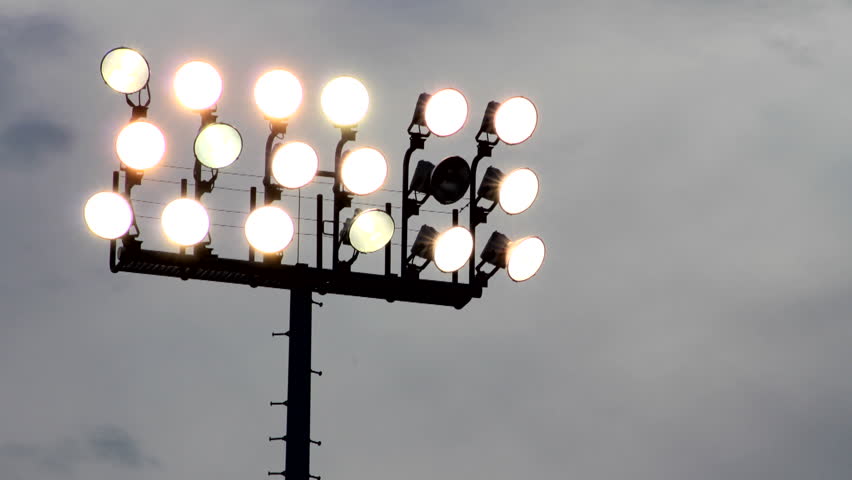 Time-lapse of clouds behind broken stadium lights.